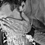 猛暑の中顔に水を浴びる男性