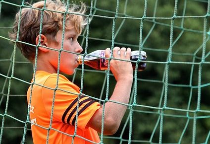 ペットボトルのスポーツドリンクを飲む子供